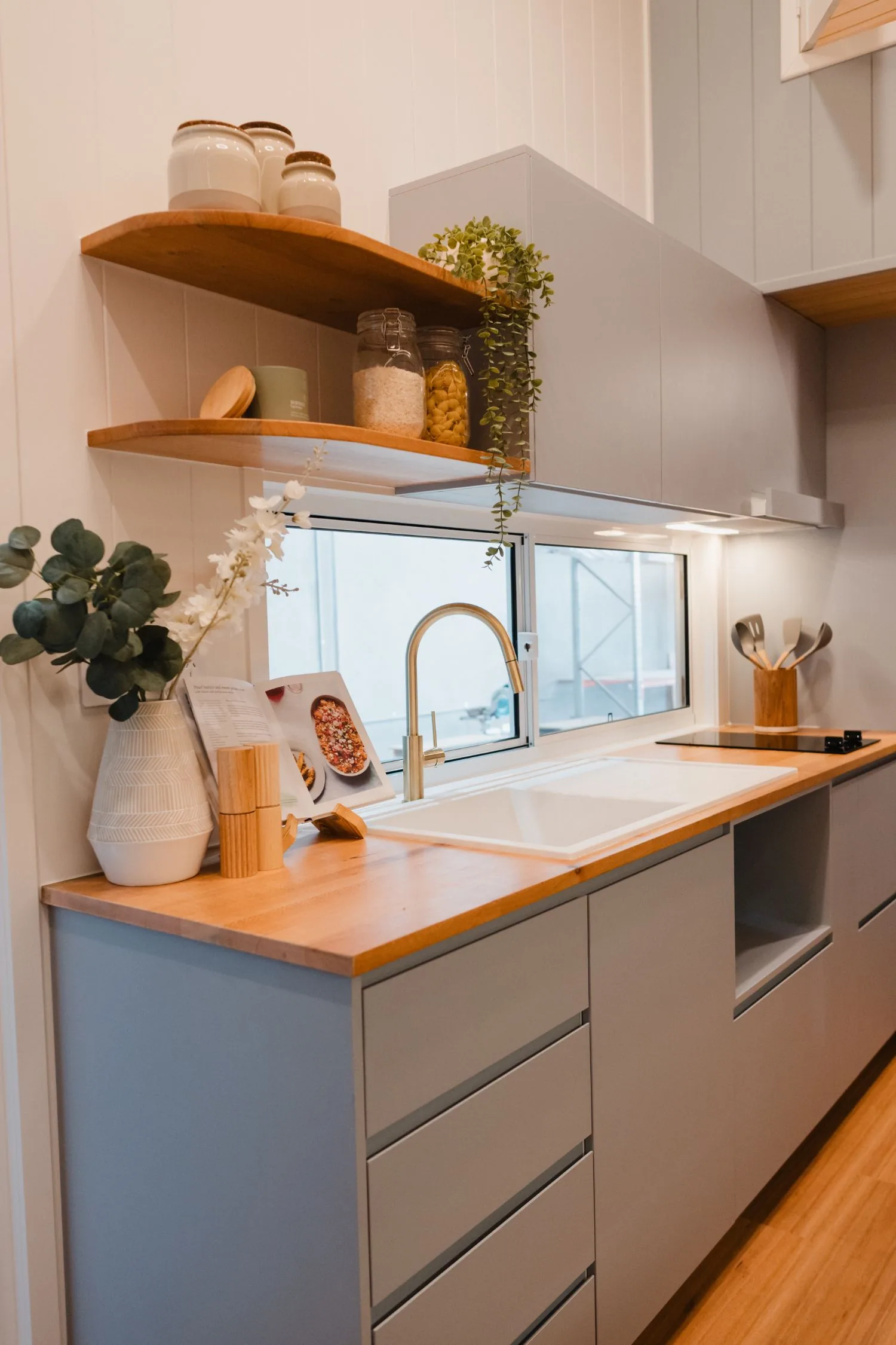 Serenity kitchen with timber benchtop, gold gooseneck tap, open shelving and induction cooktop