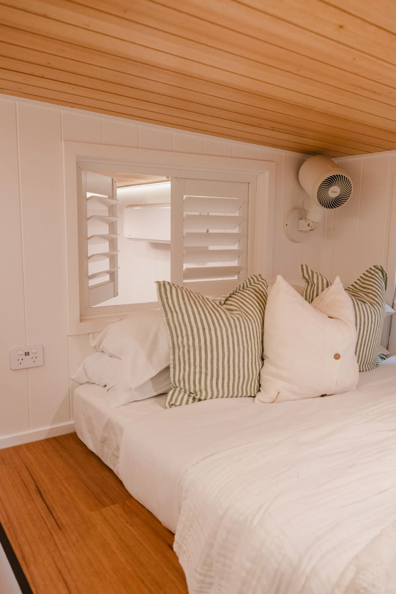 Serenity main bedroom with plantation shutter window and made bed