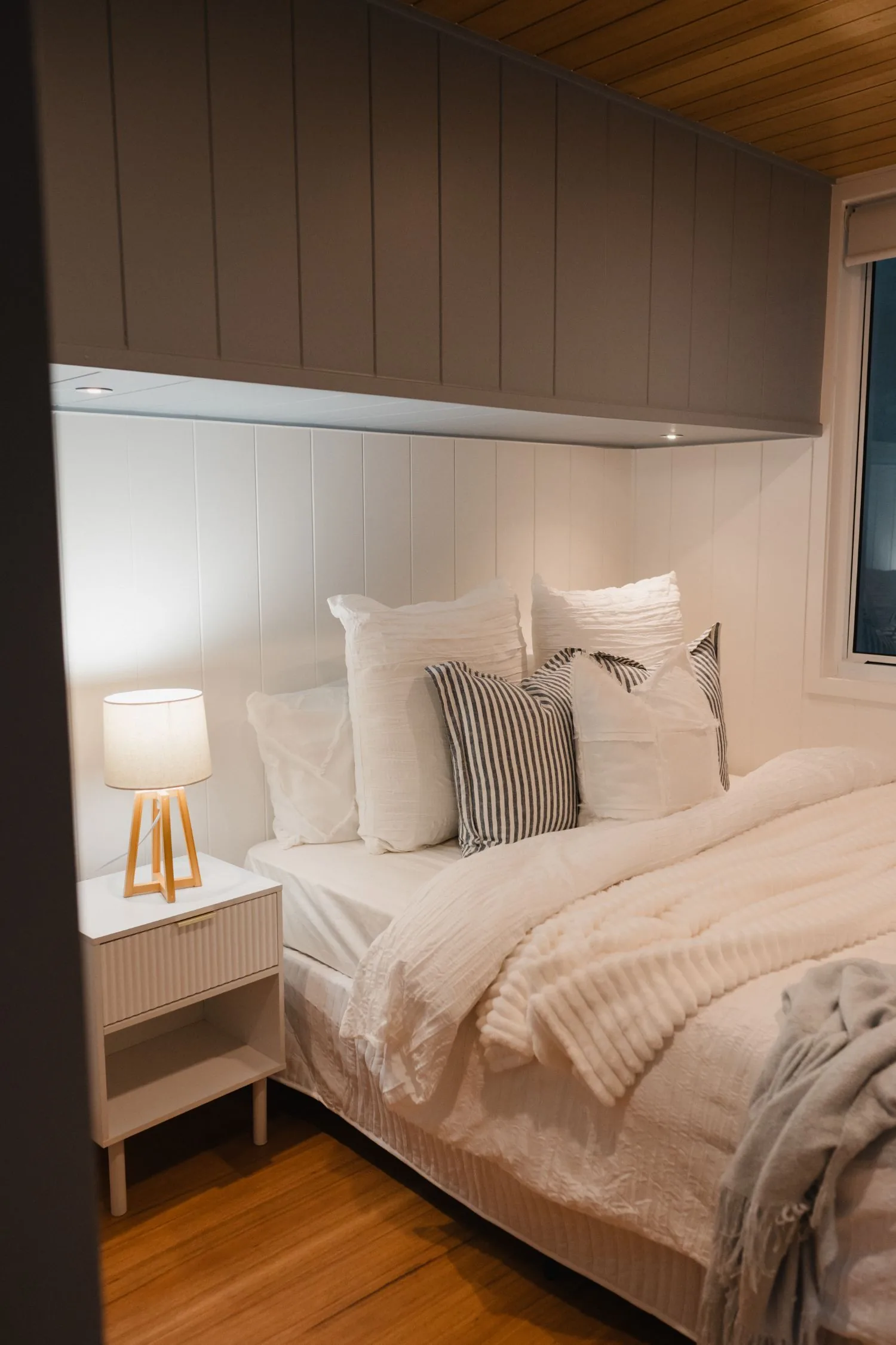 Serenity bedroom with bedside lamp, overhead cabinetry and soft bedding