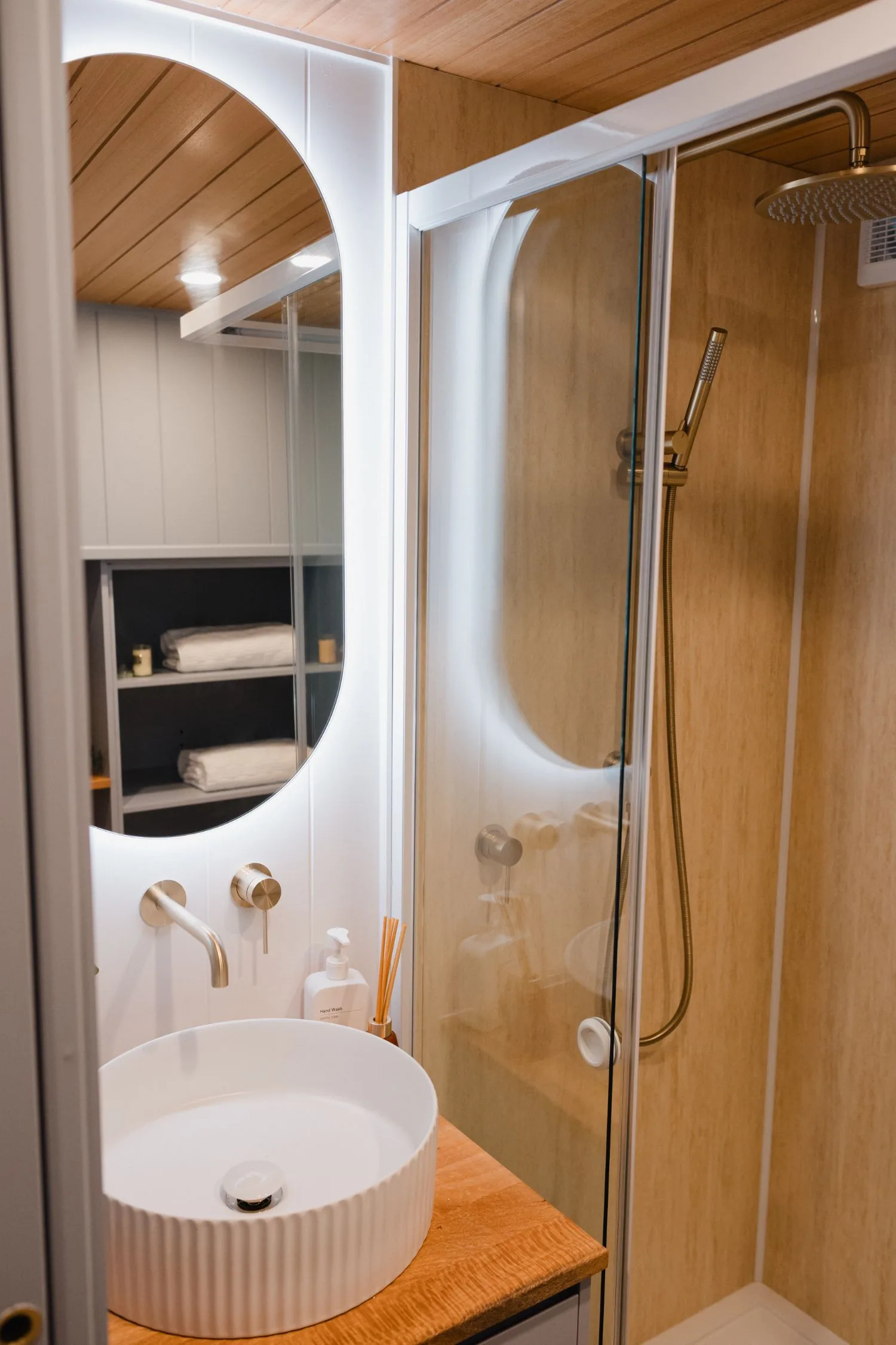 Serenity bathroom with backlit oval mirror, fluted basin and glass shower
